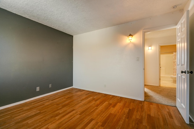 unfurnished room with hardwood / wood-style floors and a textured ceiling