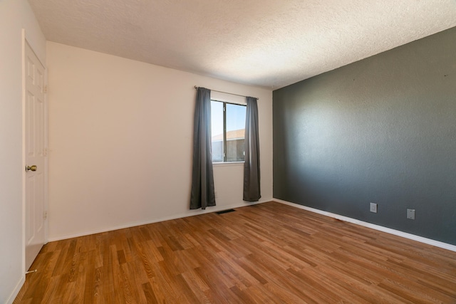 empty room featuring wood-type flooring and a textured ceiling