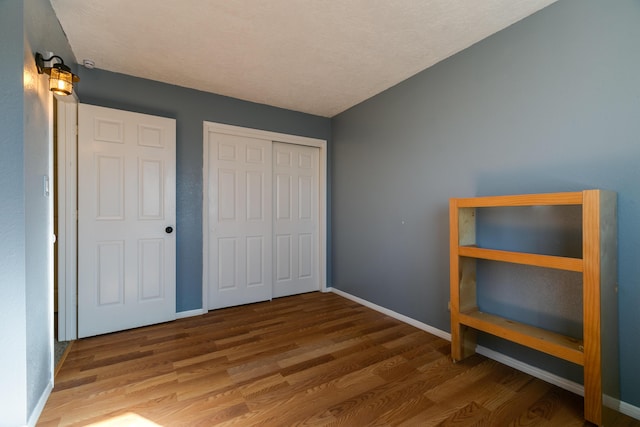 unfurnished bedroom with hardwood / wood-style floors, a textured ceiling, and a closet