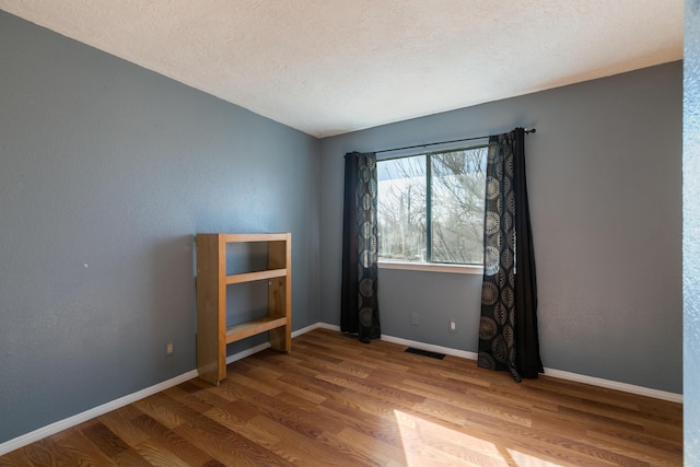 empty room featuring hardwood / wood-style flooring and a textured ceiling