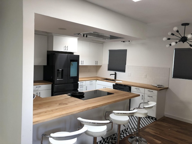 7535 Quemado Ct NE, Albuquerque, NM 87109 - kitchen featuring butcher block countertops, backsplash, black appliances, and a kitchen bar