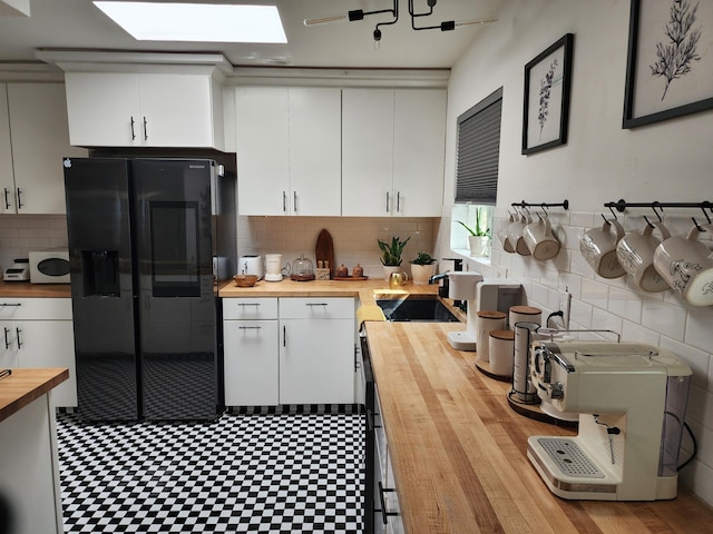 7535 Quemado Ct NE, Albuquerque, NM 87109 - kitchen featuring wooden counters, white microwave, black fridge, and white cabinetry