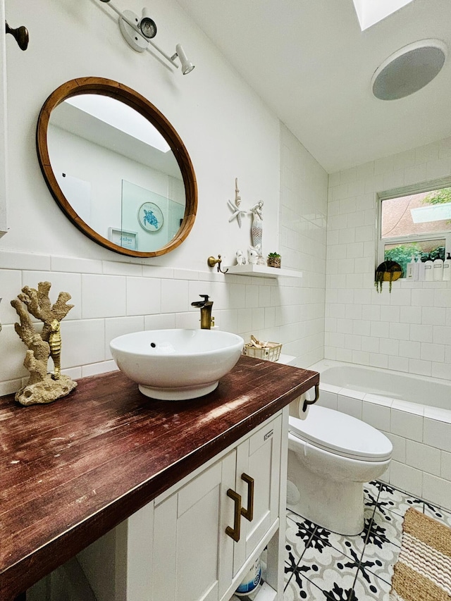 7535 Quemado Ct NE, Albuquerque, NM 87109 - bathroom with toilet, tile patterned floors, tile walls, and vanity