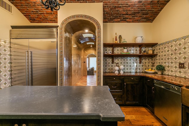 kitchen with wood-type flooring, brick ceiling, black dishwasher, and stainless steel built in refrigerator