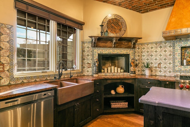 kitchen with brick ceiling, sink, light hardwood / wood-style flooring, stainless steel dishwasher, and decorative backsplash