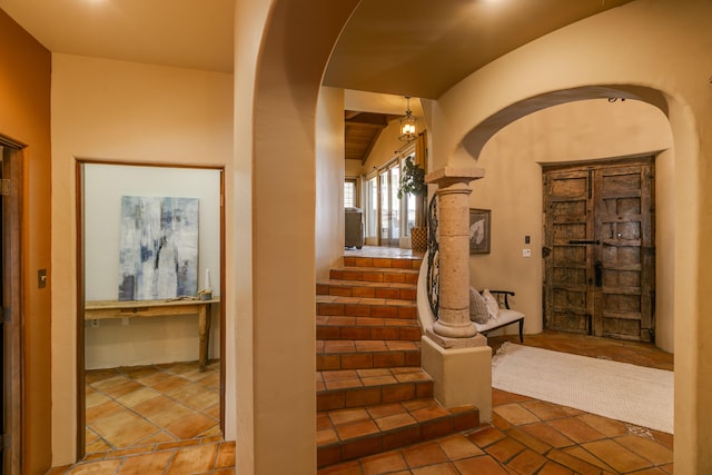 stairway featuring decorative columns and vaulted ceiling