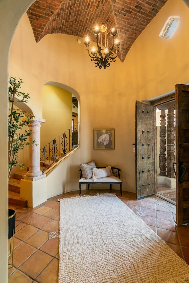 interior space featuring tile patterned flooring, brick ceiling, a towering ceiling, and a notable chandelier