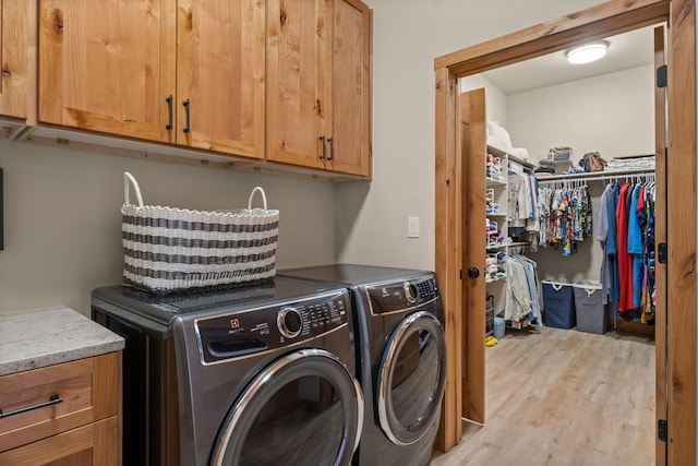 clothes washing area featuring cabinets, washer and clothes dryer, and light wood-type flooring