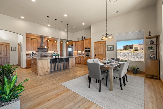 dining space with a high ceiling and light wood-type flooring