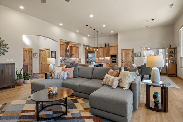 living room featuring a high ceiling, sink, and light hardwood / wood-style floors