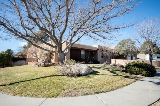 view of front of house featuring stucco siding, fence, and a front yard