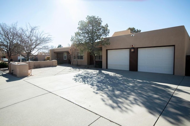 adobe home featuring concrete driveway, an attached garage, and stucco siding