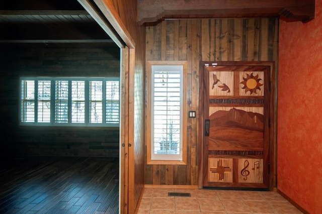 entryway featuring wood walls, tile patterned flooring, and visible vents