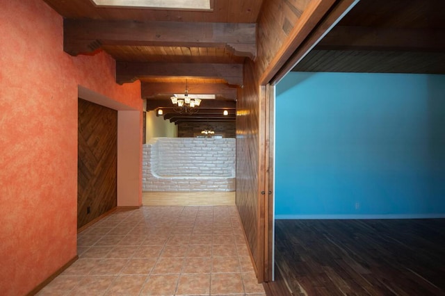 hall featuring beam ceiling, a notable chandelier, wood ceiling, baseboards, and tile patterned floors