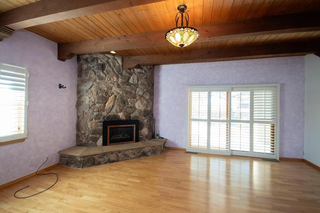 unfurnished living room with wooden ceiling, baseboards, a stone fireplace, and light wood finished floors