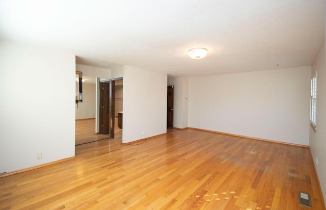 spare room featuring light wood-style flooring, visible vents, and baseboards