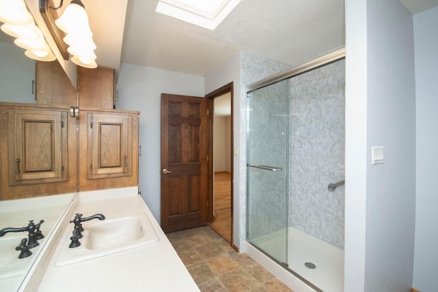 bathroom with a skylight, vanity, and a shower stall