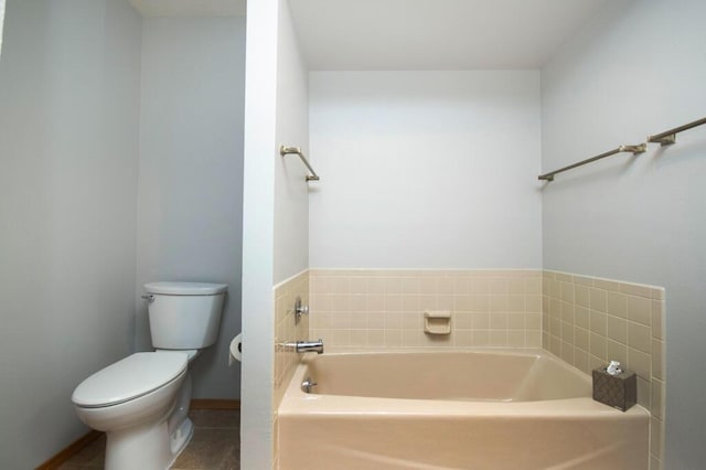 full bathroom featuring toilet, a bath, and baseboards