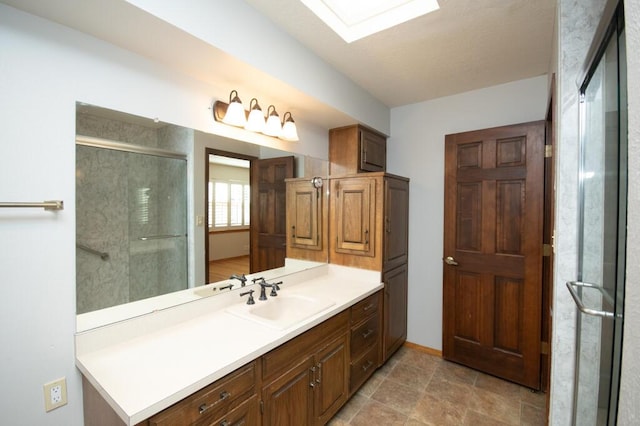 bathroom with a skylight, an enclosed shower, and vanity