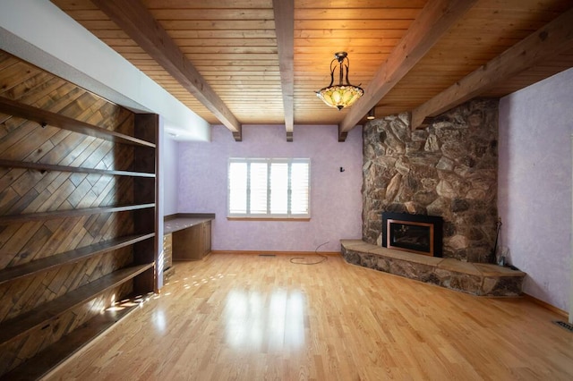 unfurnished living room with light wood finished floors, wood ceiling, a fireplace, and beamed ceiling