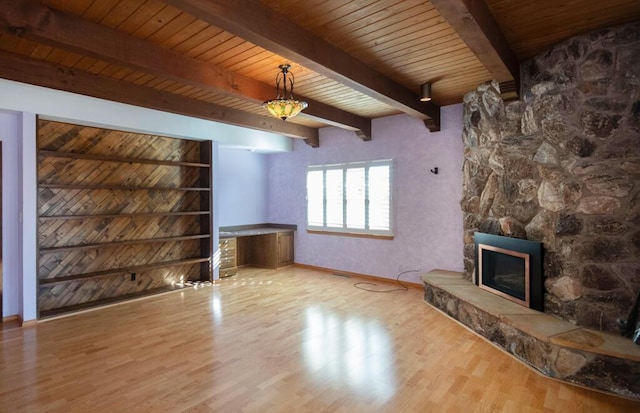 unfurnished living room with light wood-style floors, wooden ceiling, a fireplace, and beamed ceiling