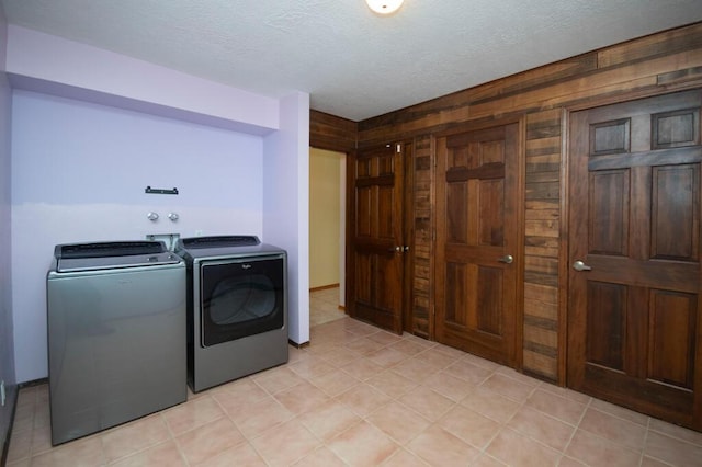 laundry area featuring wooden walls, washer and dryer, laundry area, and a textured ceiling