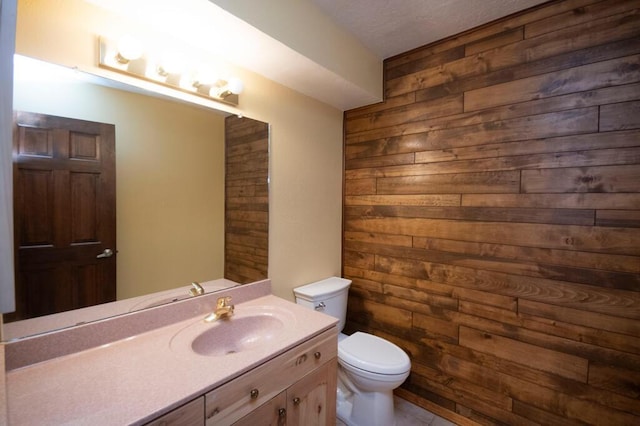 half bath featuring wood walls, vanity, and toilet