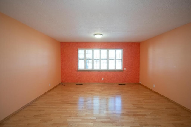 unfurnished room with light wood-style flooring, visible vents, and baseboards