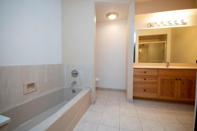 bathroom featuring baseboards, toilet, tile patterned floors, a garden tub, and vanity