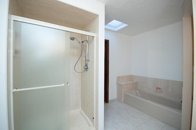 bathroom featuring a shower stall, a skylight, a garden tub, and tile patterned floors