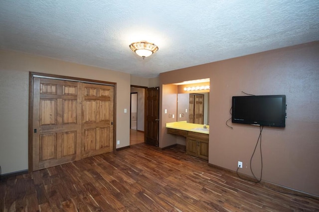 unfurnished bedroom with a textured ceiling, dark wood-style flooring, and built in study area