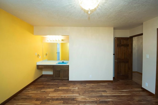 interior space featuring a textured ceiling, vanity, baseboards, and wood finished floors