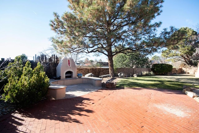 view of patio / terrace featuring exterior fireplace and fence