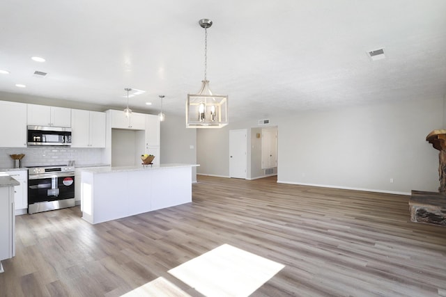 kitchen featuring tasteful backsplash, hanging light fixtures, a kitchen island, stainless steel appliances, and white cabinets