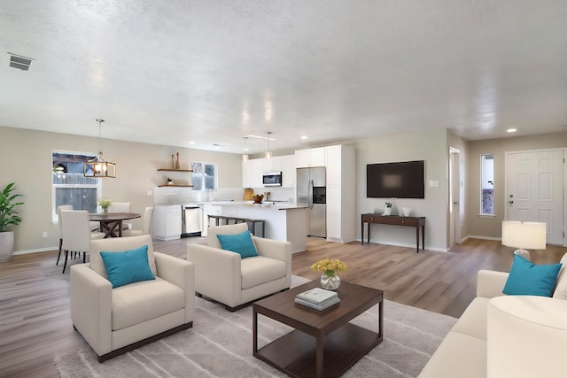 living room with sink, light hardwood / wood-style flooring, and a textured ceiling