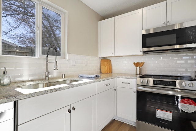 kitchen featuring white cabinetry, sink, light stone counters, and appliances with stainless steel finishes