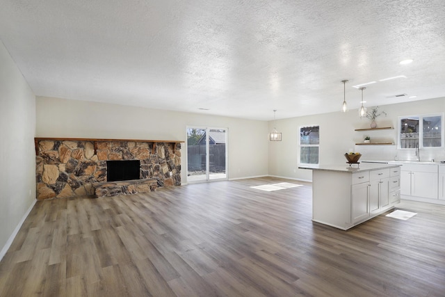 unfurnished living room featuring wood-type flooring, sink, a textured ceiling, and a fireplace