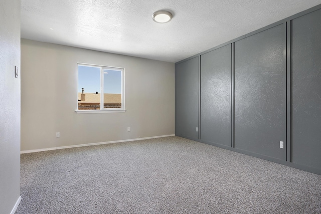 unfurnished room featuring a textured ceiling and carpet flooring