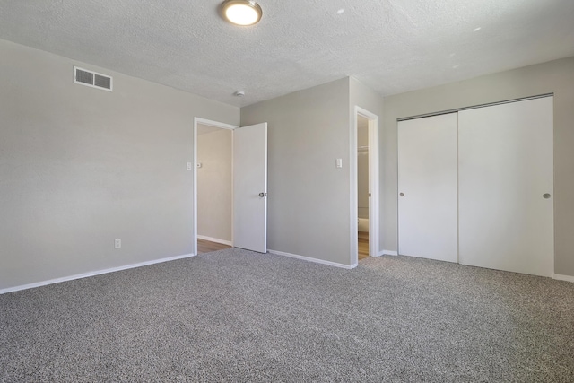 unfurnished bedroom featuring carpet, a textured ceiling, and a closet