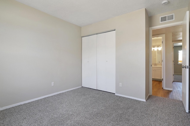 unfurnished bedroom featuring carpet floors, a textured ceiling, and a closet