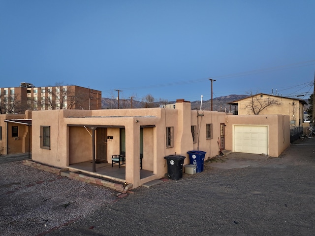 pueblo-style home with a garage and a patio