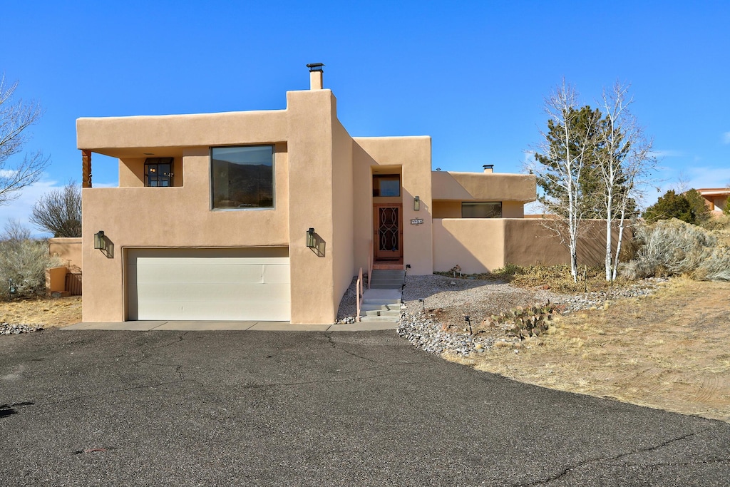 southwest-style home featuring a garage, fence, and stucco siding