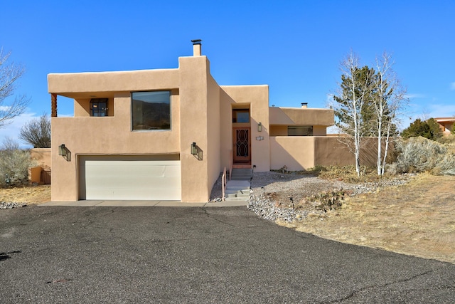 southwest-style home featuring a garage, fence, and stucco siding