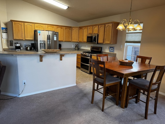 kitchen featuring lofted ceiling, a breakfast bar, appliances with stainless steel finishes, hanging light fixtures, and kitchen peninsula