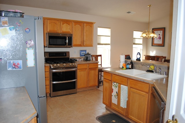 kitchen featuring light tile patterned flooring, sink, a chandelier, pendant lighting, and stainless steel appliances