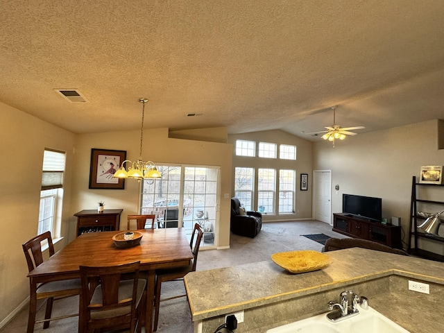 carpeted dining area featuring vaulted ceiling, ceiling fan with notable chandelier, and a textured ceiling