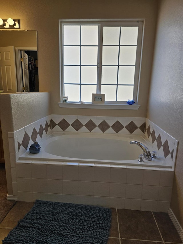 bathroom featuring a relaxing tiled tub, a healthy amount of sunlight, and tile patterned floors