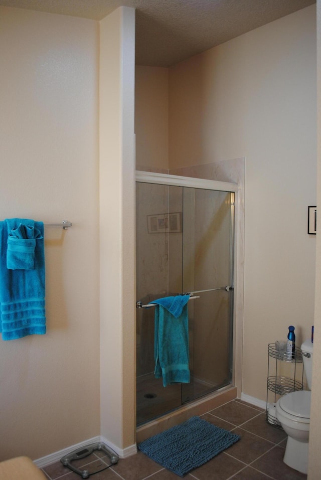 bathroom with tile patterned flooring, an enclosed shower, and toilet