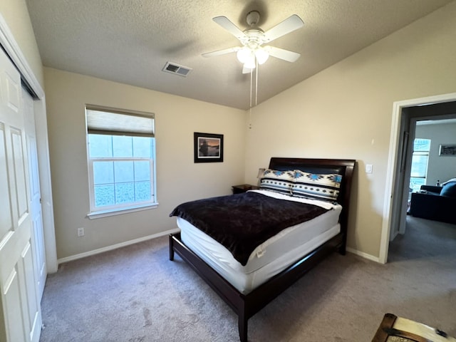 carpeted bedroom with lofted ceiling, ceiling fan, a closet, and a textured ceiling