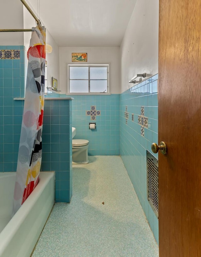 bathroom with tile walls, shower / bathtub combination with curtain, and toilet